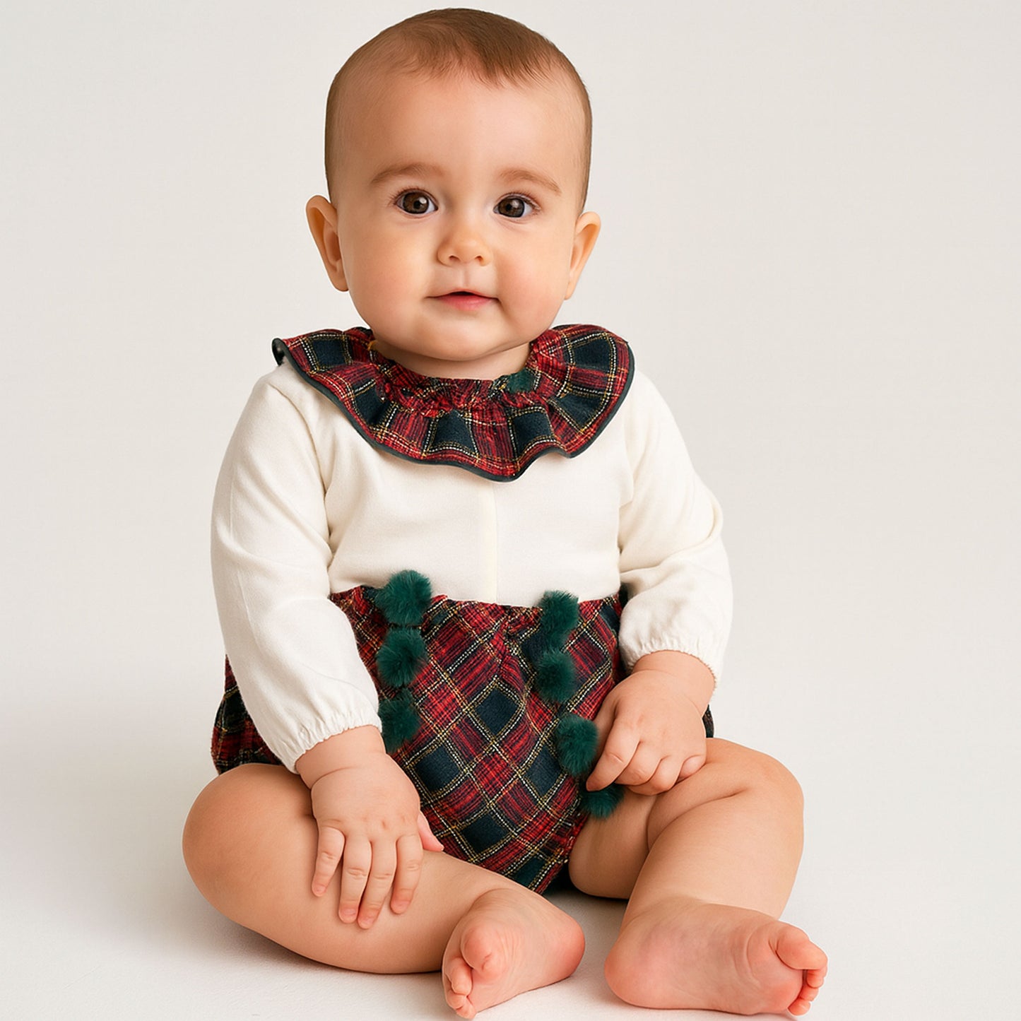 Baby wearing a plaid outfit with a white background