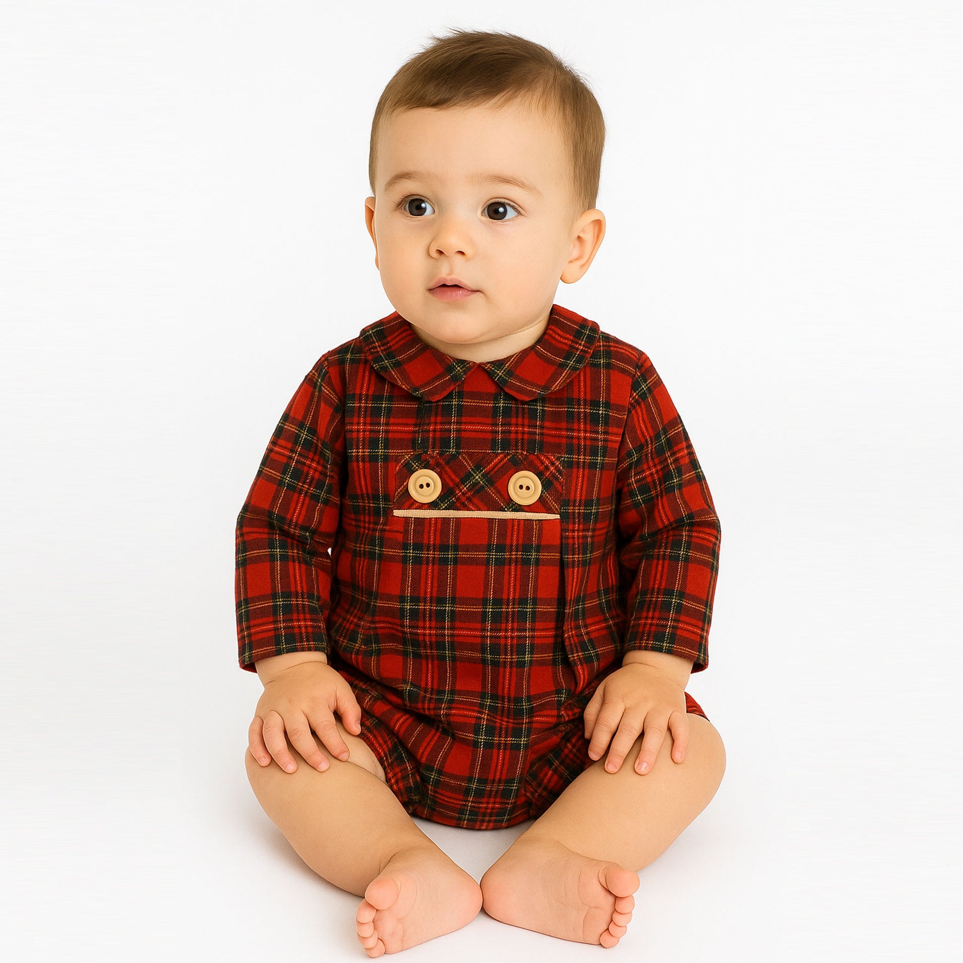 Baby wearing a red plaid outfit with button details on a white background