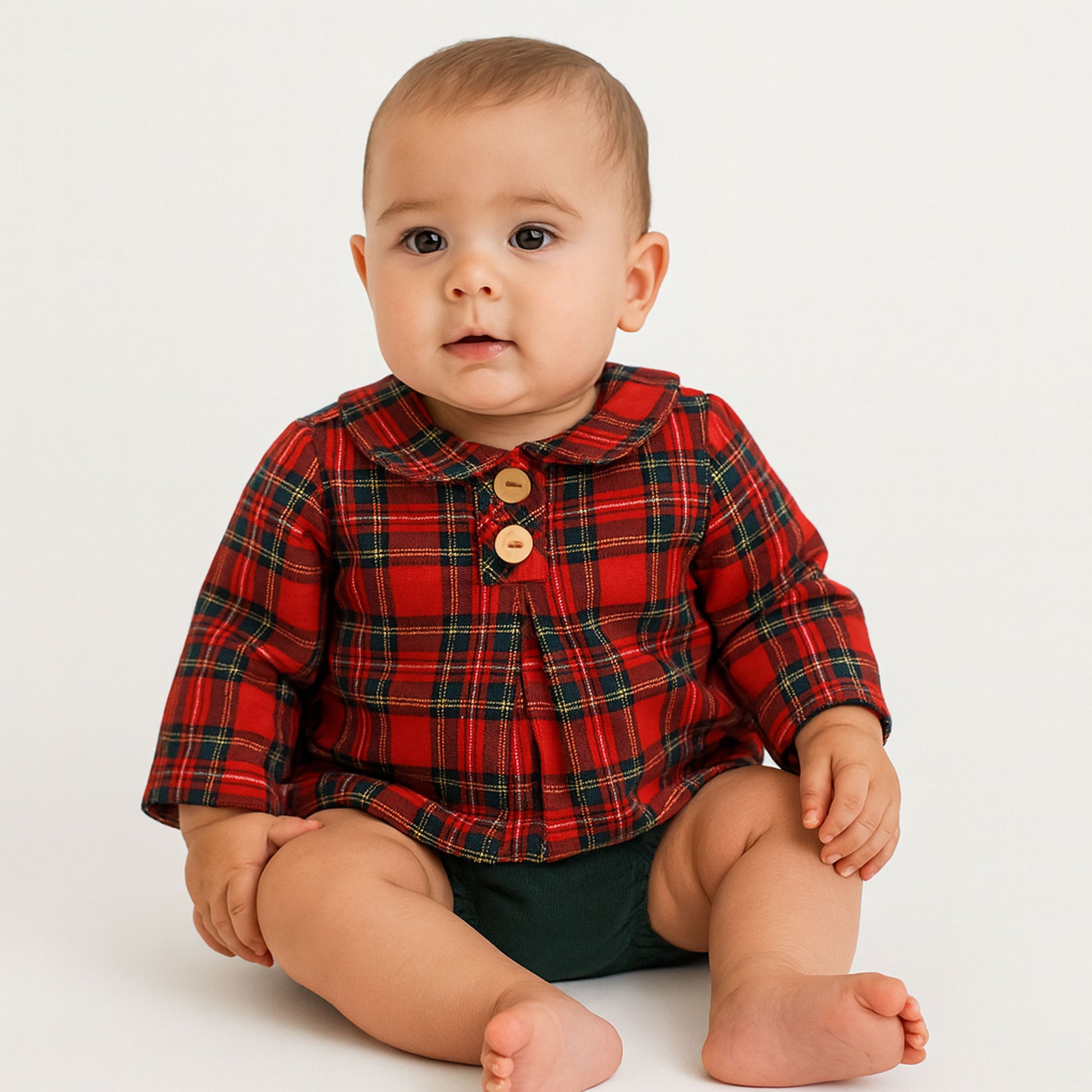 Baby wearing a red plaid shirt with buttons on a white background