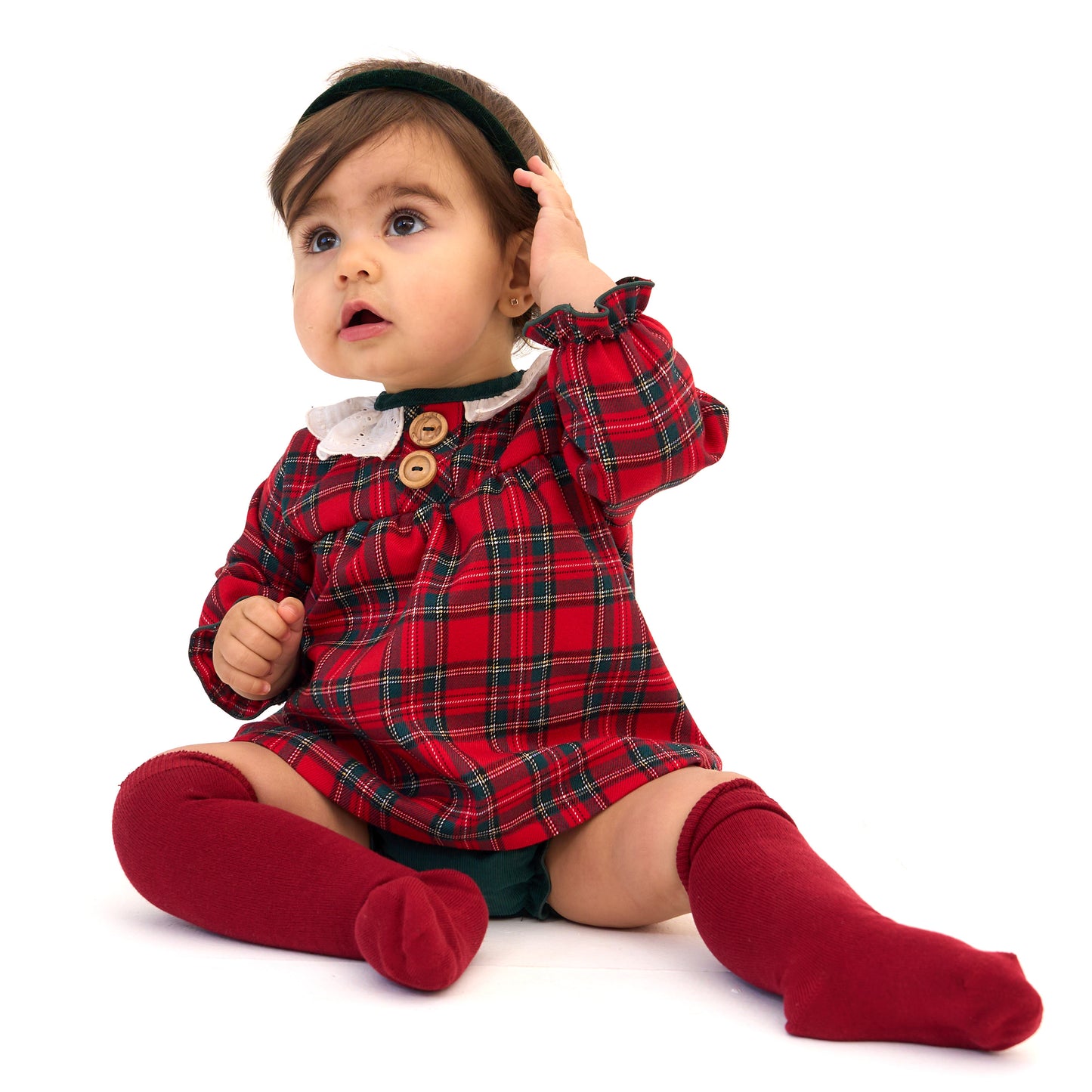Baby wearing a red plaid outfit with a white background