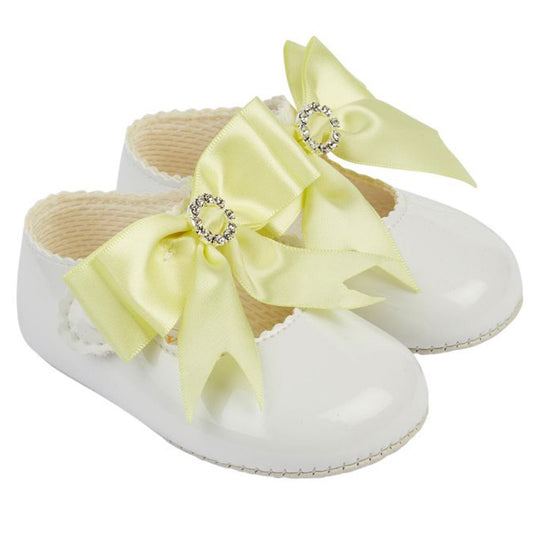 White baby shoes with large yellow bows on a white background