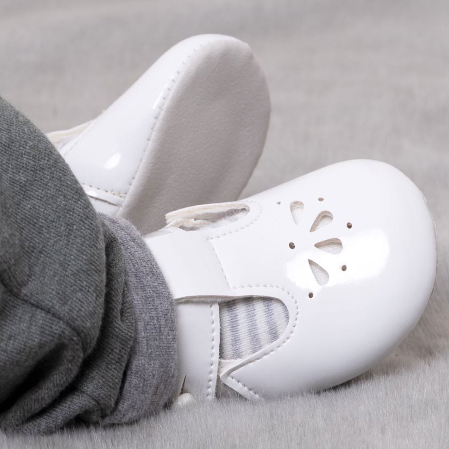 White baby shoes with gray socks on a light gray background