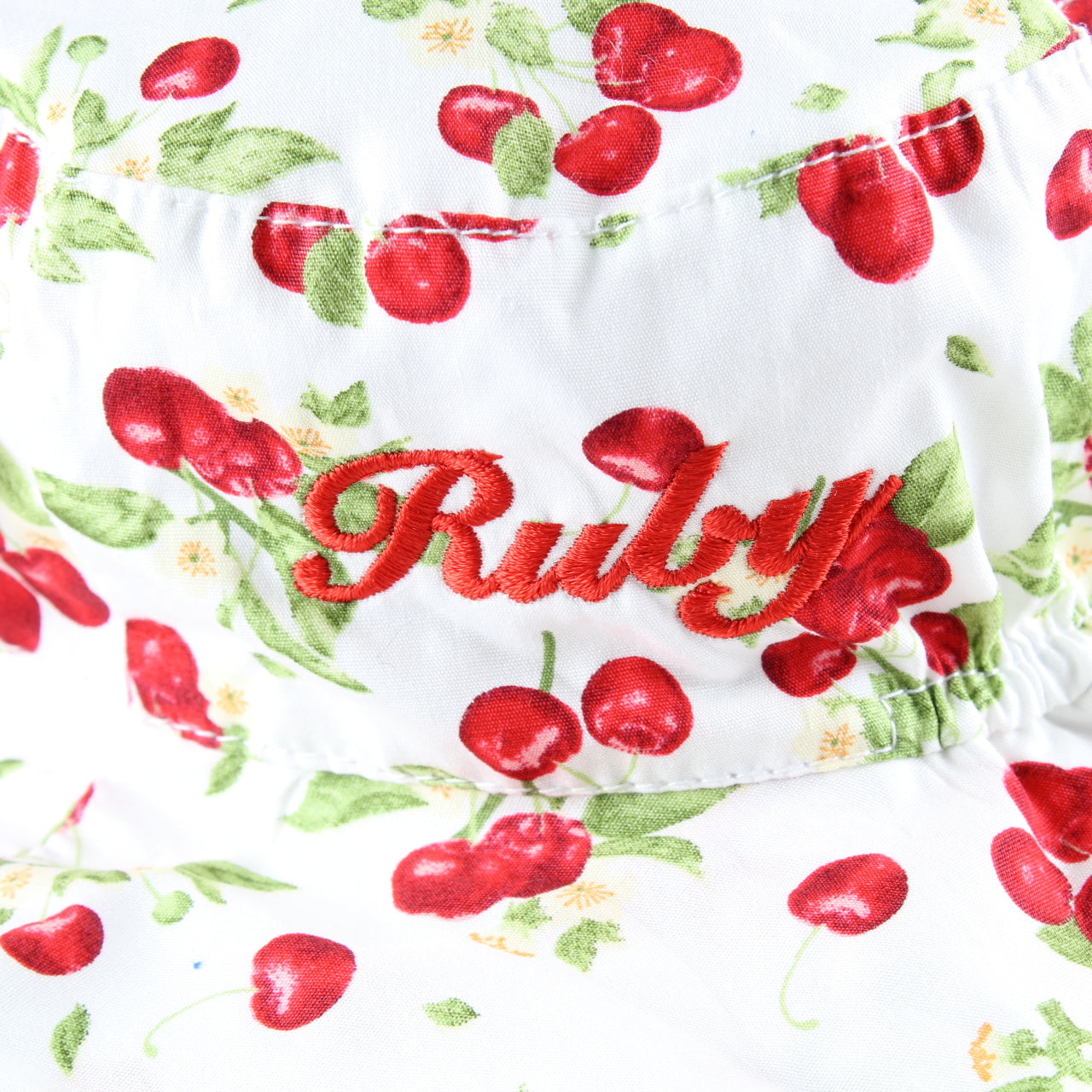 Fabric with red cherries and the word 'Ruby' embroidered on a white background