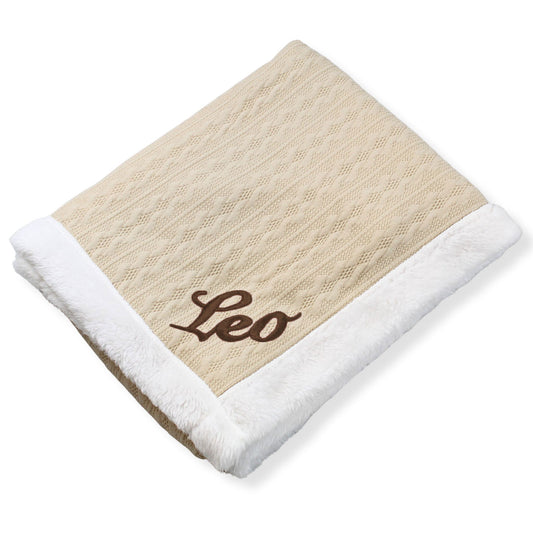 Beige blanket with white trim and 'Leo' embroidery on a white background