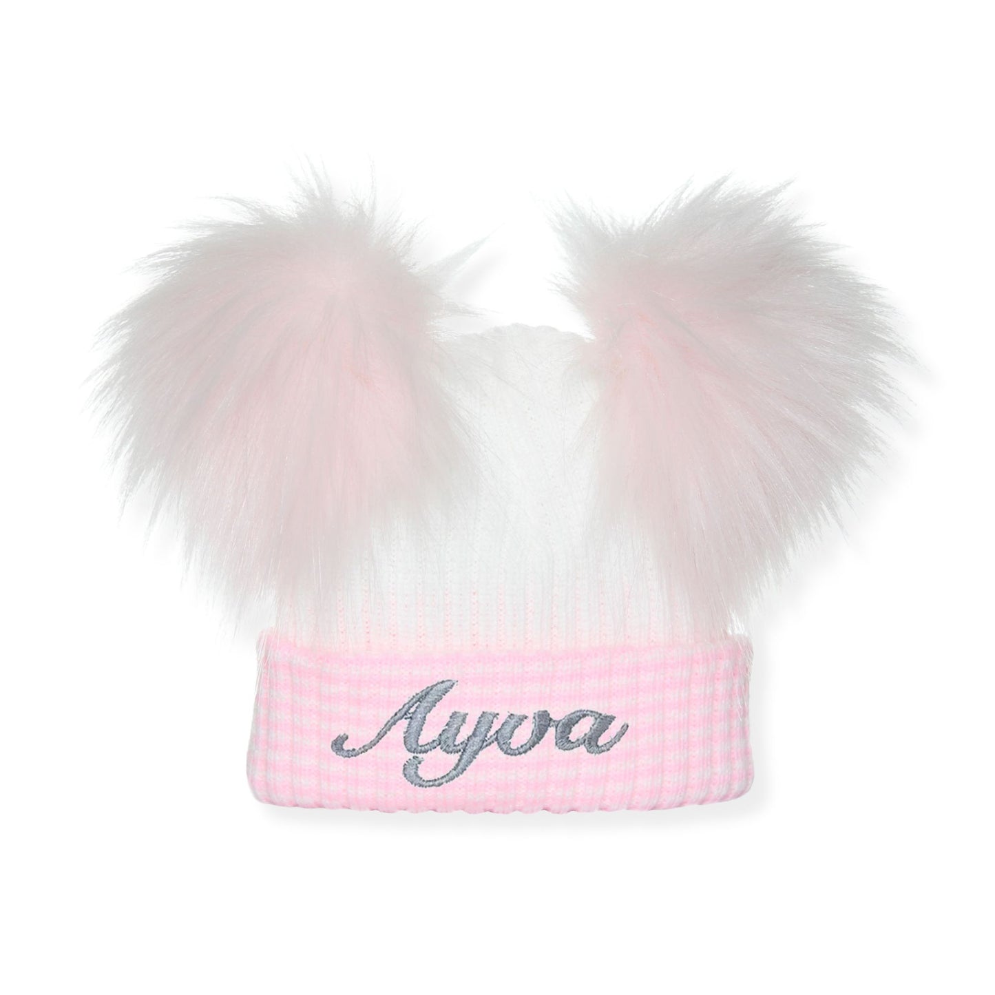 Pink beanie with white fur pom-poms and 'Ayva' embroidery on a white background
