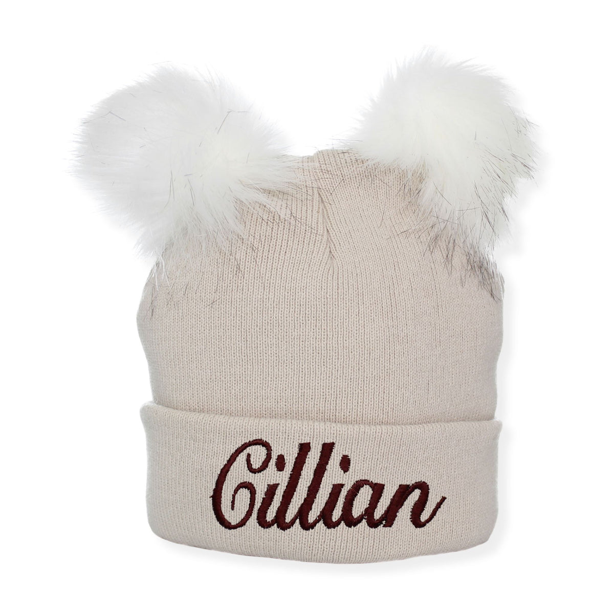 Beige knit beanie with white fur pom-poms and embroidered name 'Cillian' on a white background