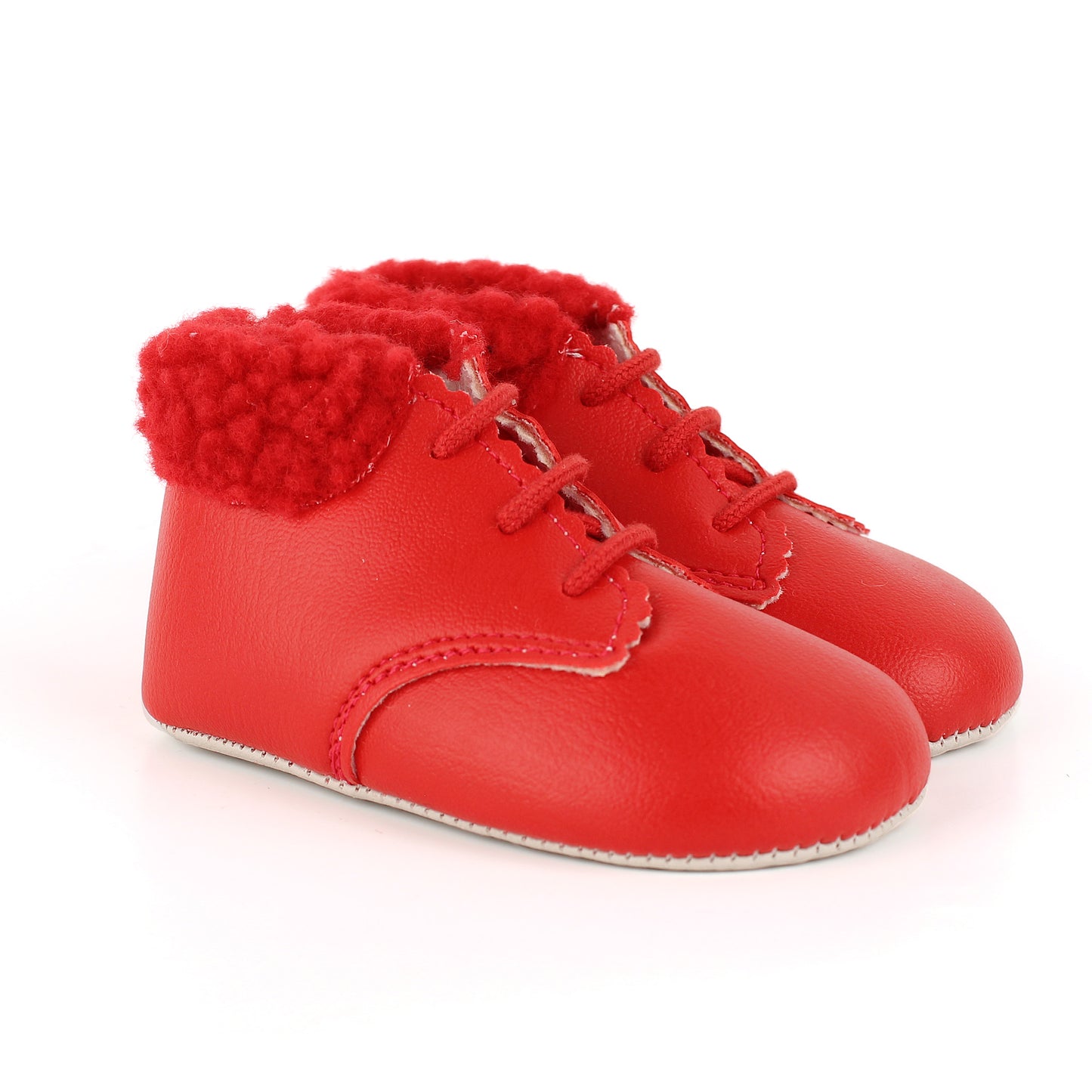 A pair of baby booties in bright red faux leather with red laces and a fluffy red faux-fur trim around the collar, shown on a white background.
