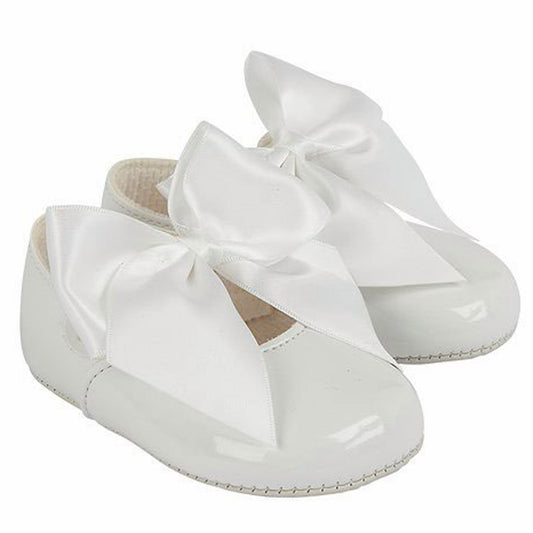 White patent leather shoes with large bows on a white background