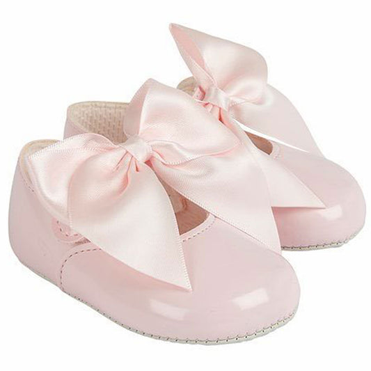 Pink baby shoes with large bows on a white background
