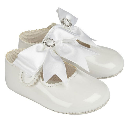 White baby shoes with bows and embellishments on a white background