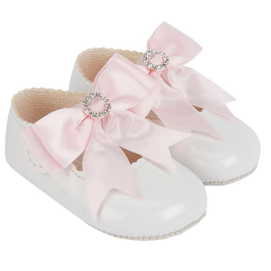 White baby shoes with pink bows on a white background