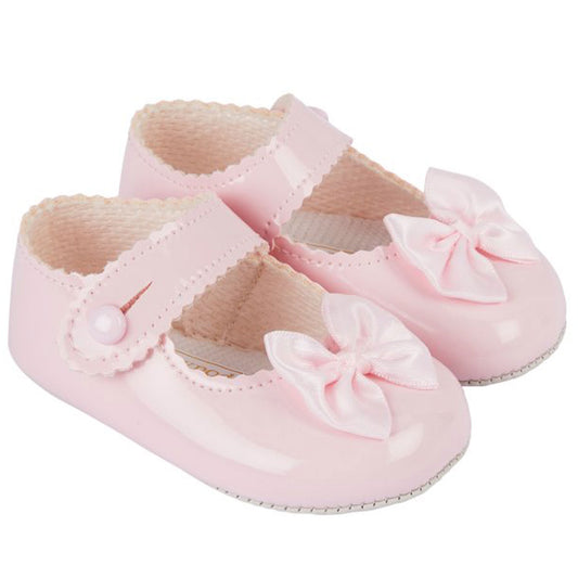 Pink baby shoes with bows on a white background