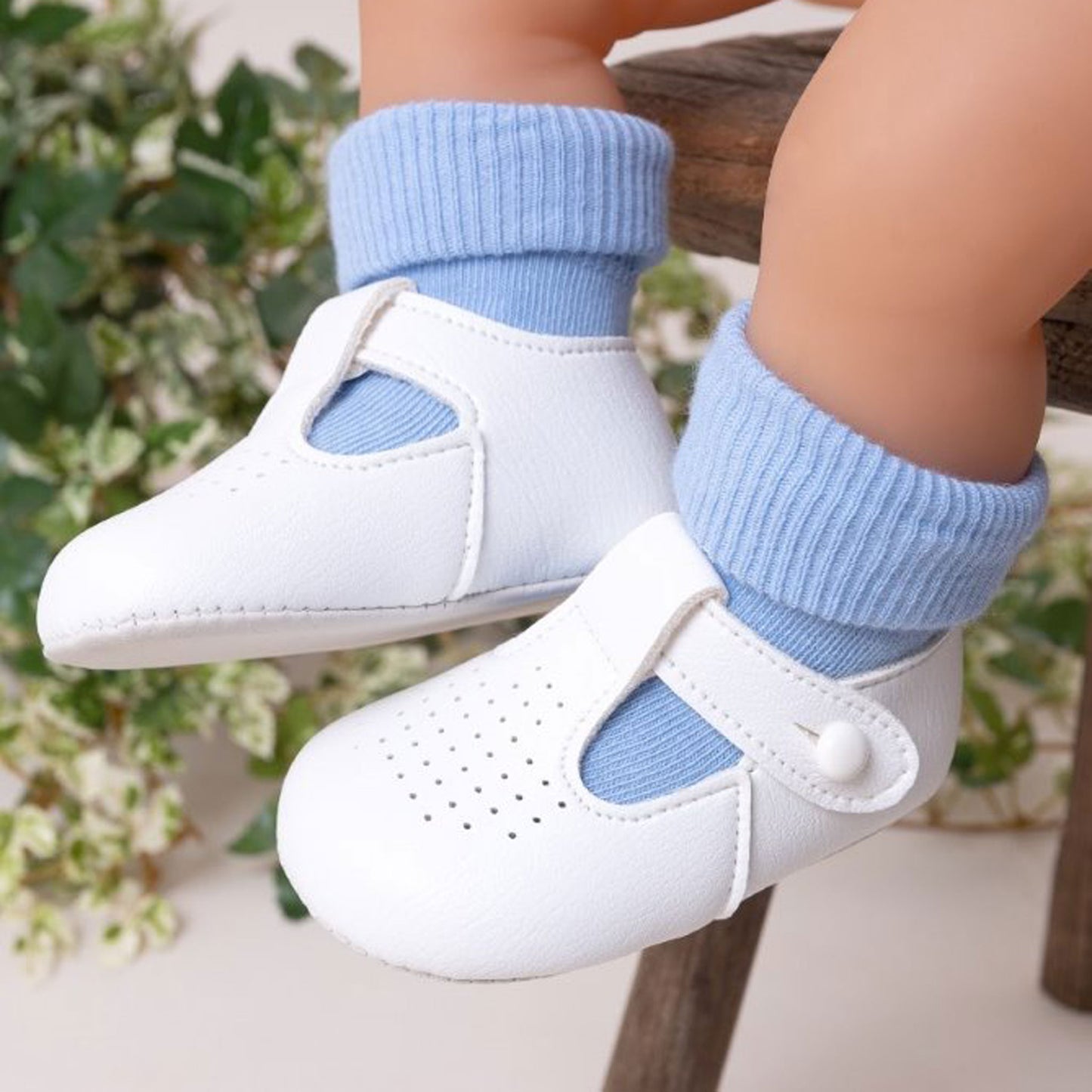 White shoes with blue socks worn by a child, against a blurred natural background