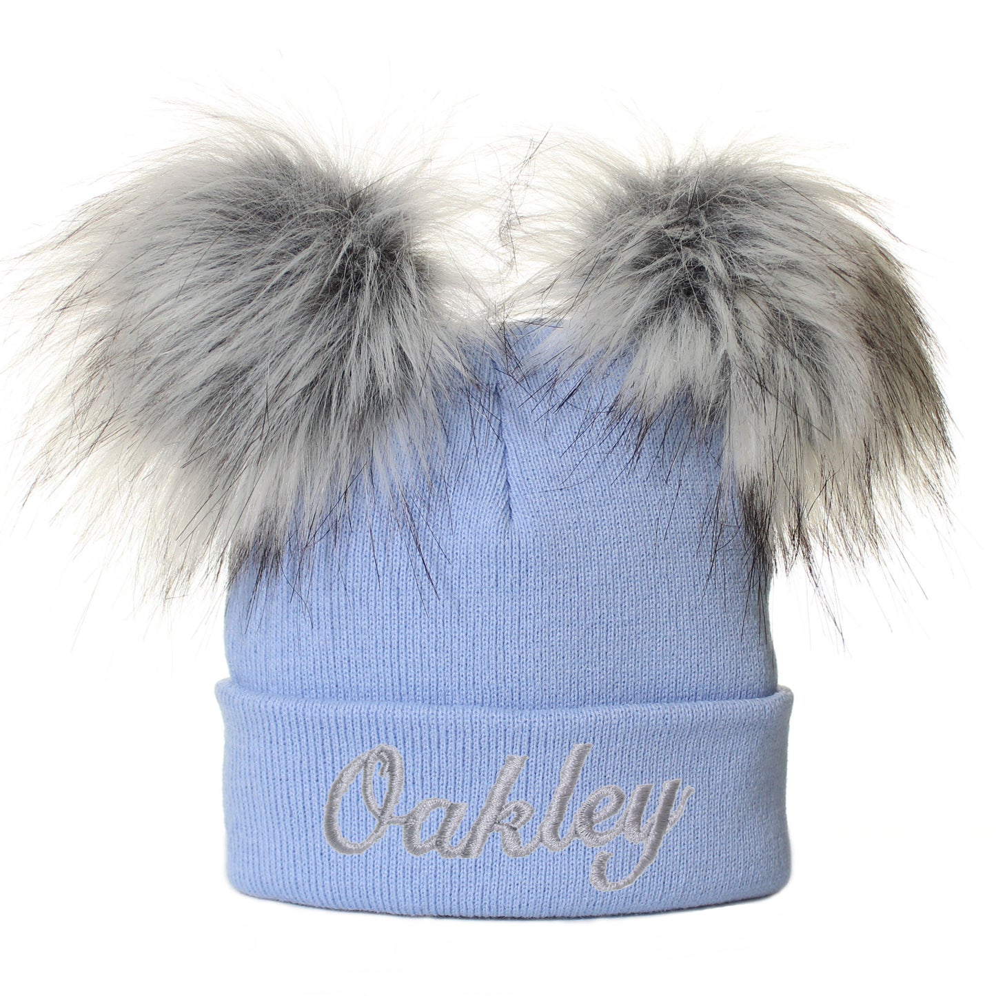 Blue beanie with fur pom-poms and 'Oakley' name on a white background