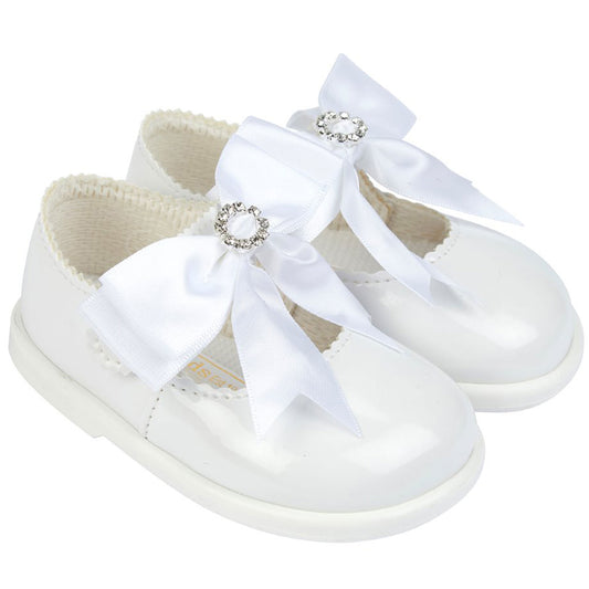 White baby shoes with decorative bows on a white background