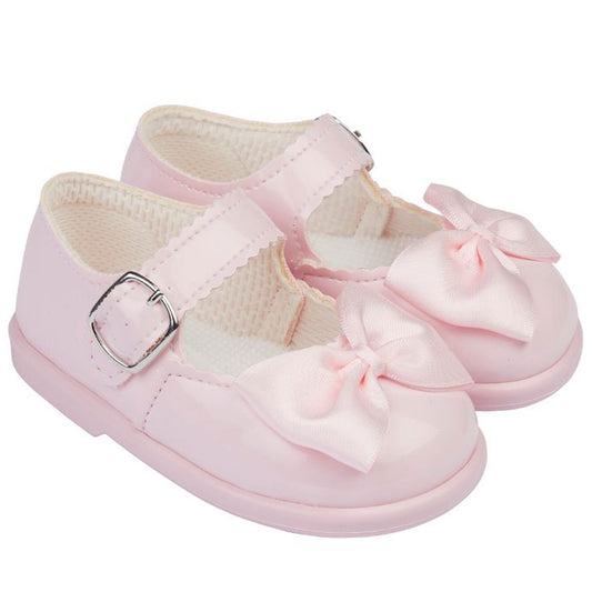 Pink baby shoes with bows on a white background