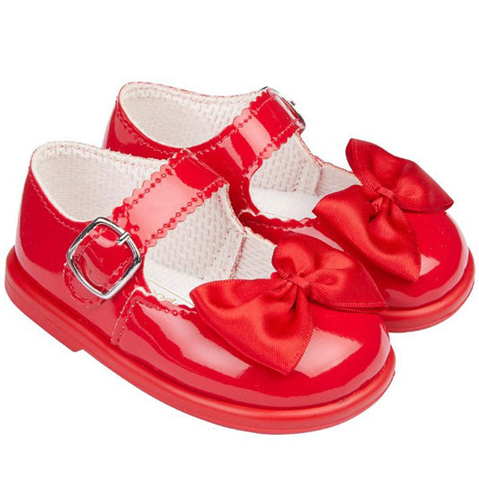Red patent leather shoes with bows on a white background