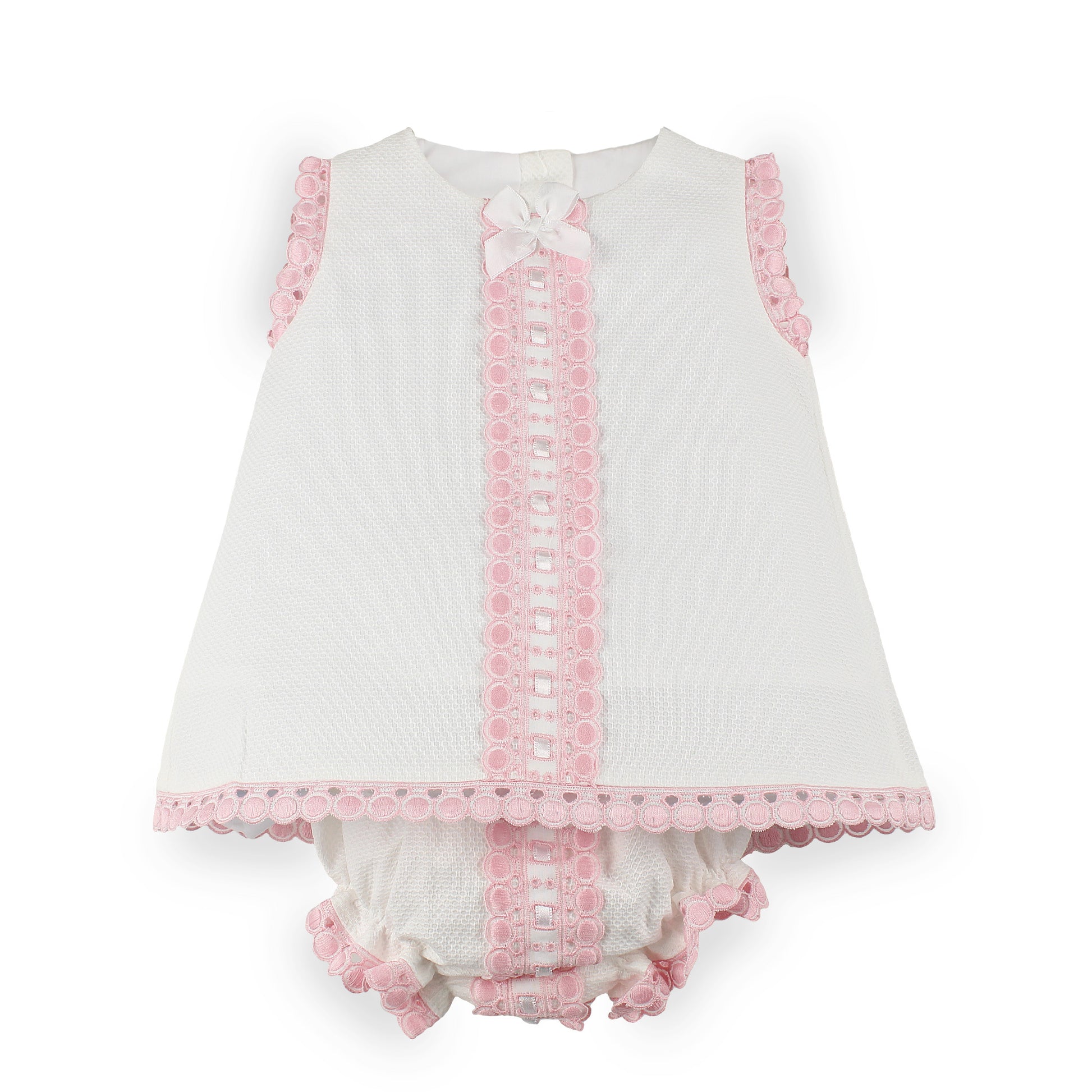 A baby girl's sleeveless white dress with pink lace trim, a matching pink lace front panel, a white bow at the neckline, and matching ruffled bloomers.