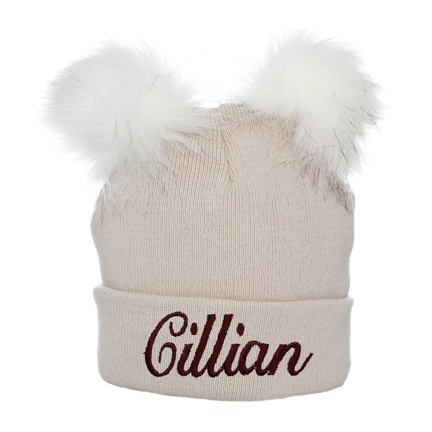 Beige beanie with white fur pom-poms and 'Gillian' embroidery on a white background