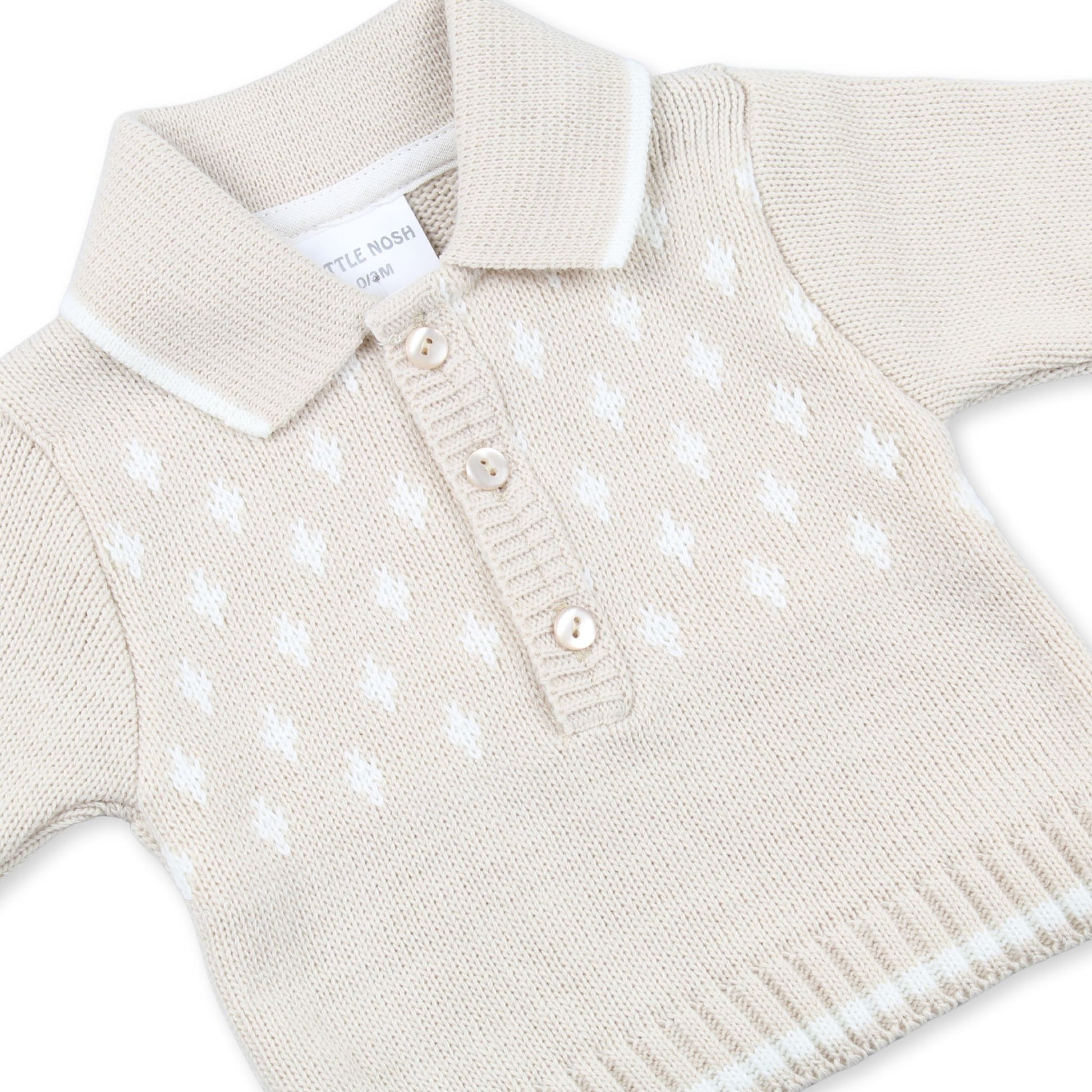 Beige knitted sweater with white polka dots on a white background