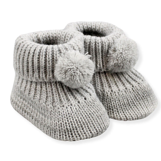 Pair of gray knitted baby booties with pom-poms on a white background