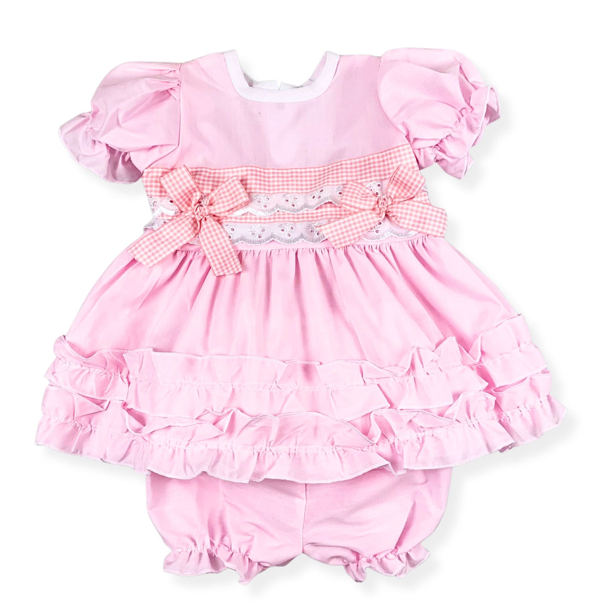 Pink baby dress with ruffles and matching bloomers on a white background
