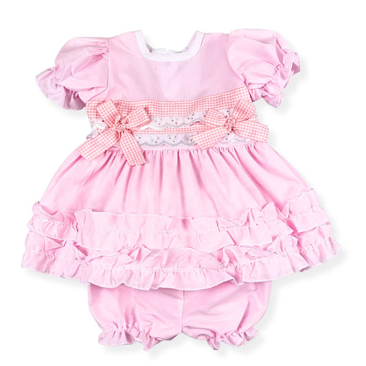 Pink baby dress with ruffles and matching bloomers on a white background
