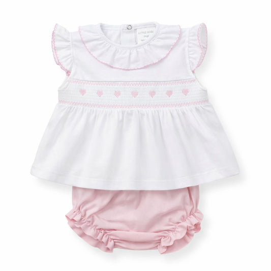 Baby outfit with white top and pink bloomers on a white background