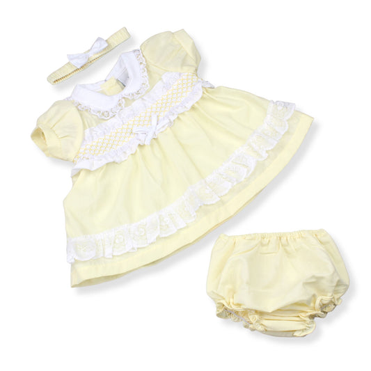 Yellow baby dress with white ruffles and matching bloomers on a white background