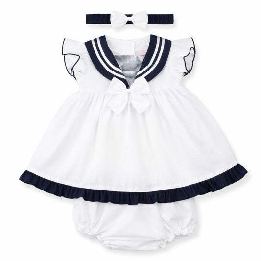 White baby dress with navy trim and matching headband on a white background