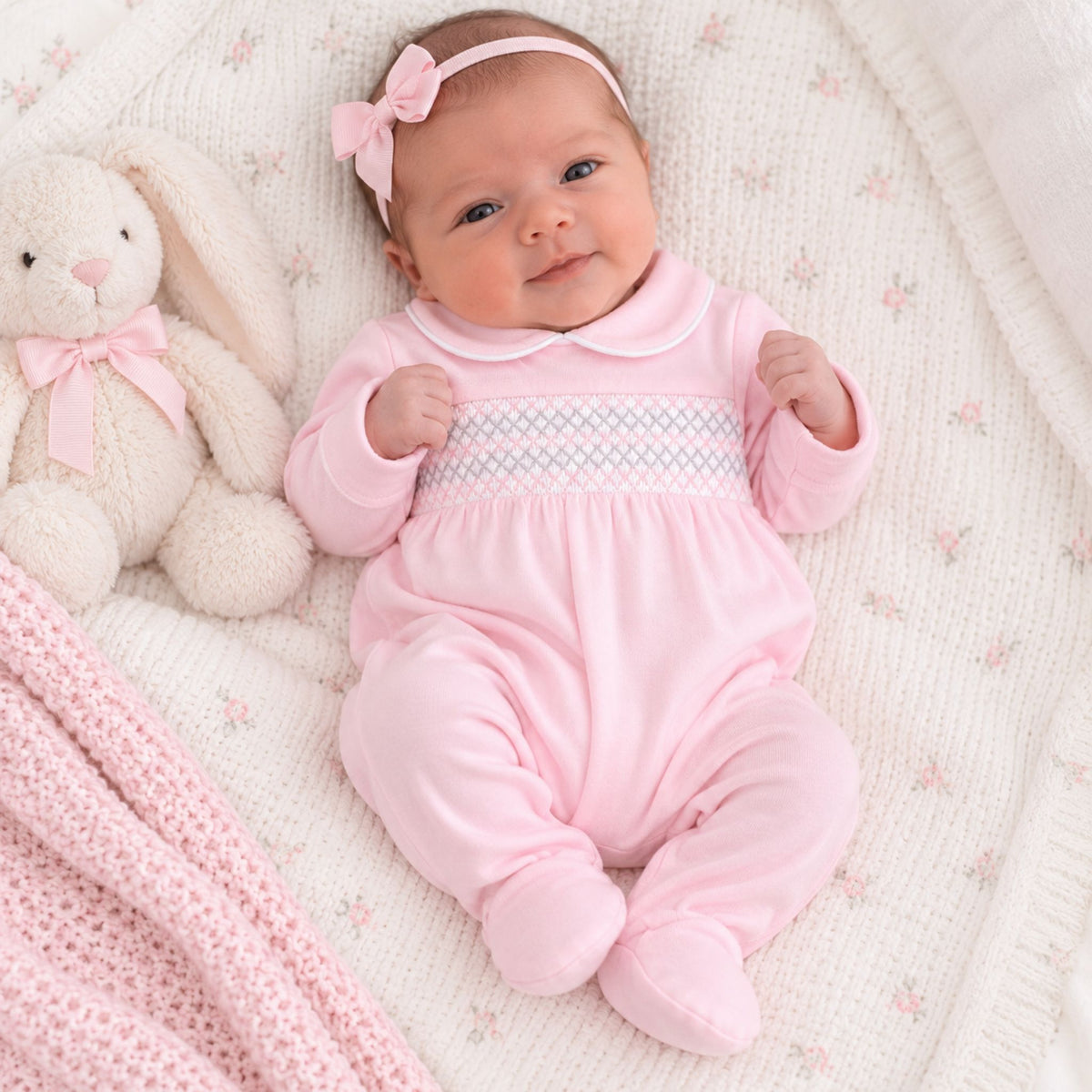 baby girl in pink babygrow with pink and white smocking