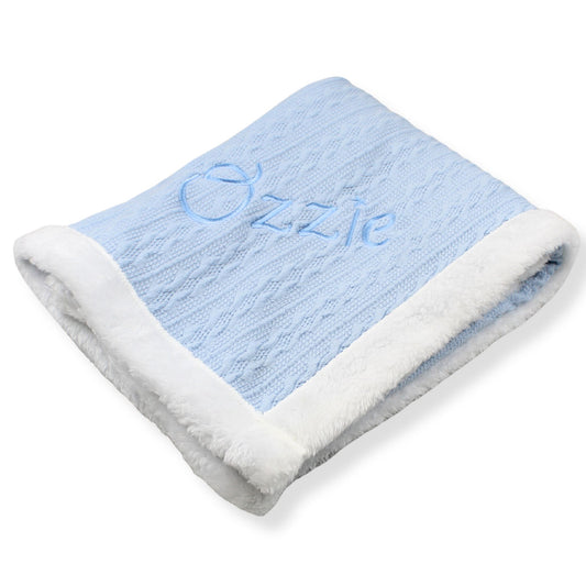 Blue baby blanket with white border and 'Ozzie' embroidery on a white background