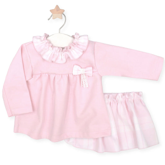 Pink baby dress with ruffled collar and white trim on a white background