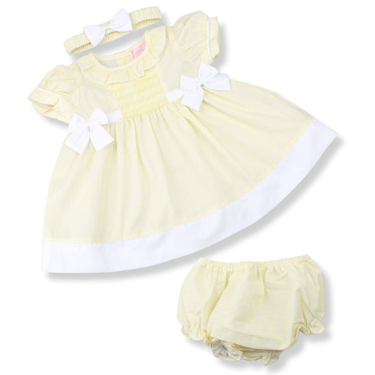 Yellow baby dress with white trim and matching bloomers on a white background