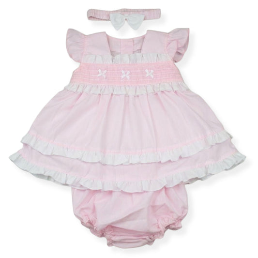 Pink baby dress with ruffles, bloomers, and headband on a white background