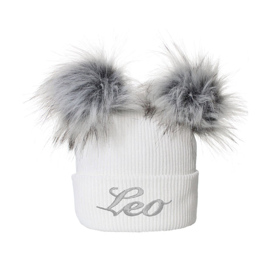 White beanie with gray faux fur pom-poms and 'Leo' embroidery on a white background