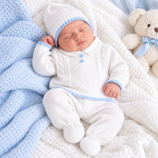 Baby boys white knitted three piece outfit with blue trim, footed trousers and matching hat
