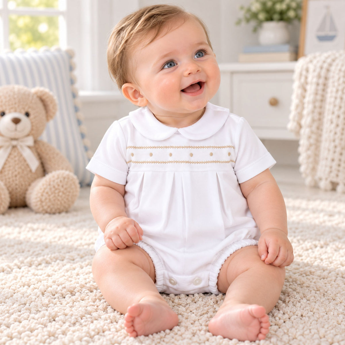 baby boy in a white romper with beige embroidery