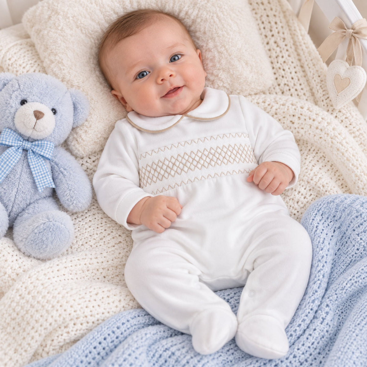 baby boy in white sleepsuit babygrow with beige smocking