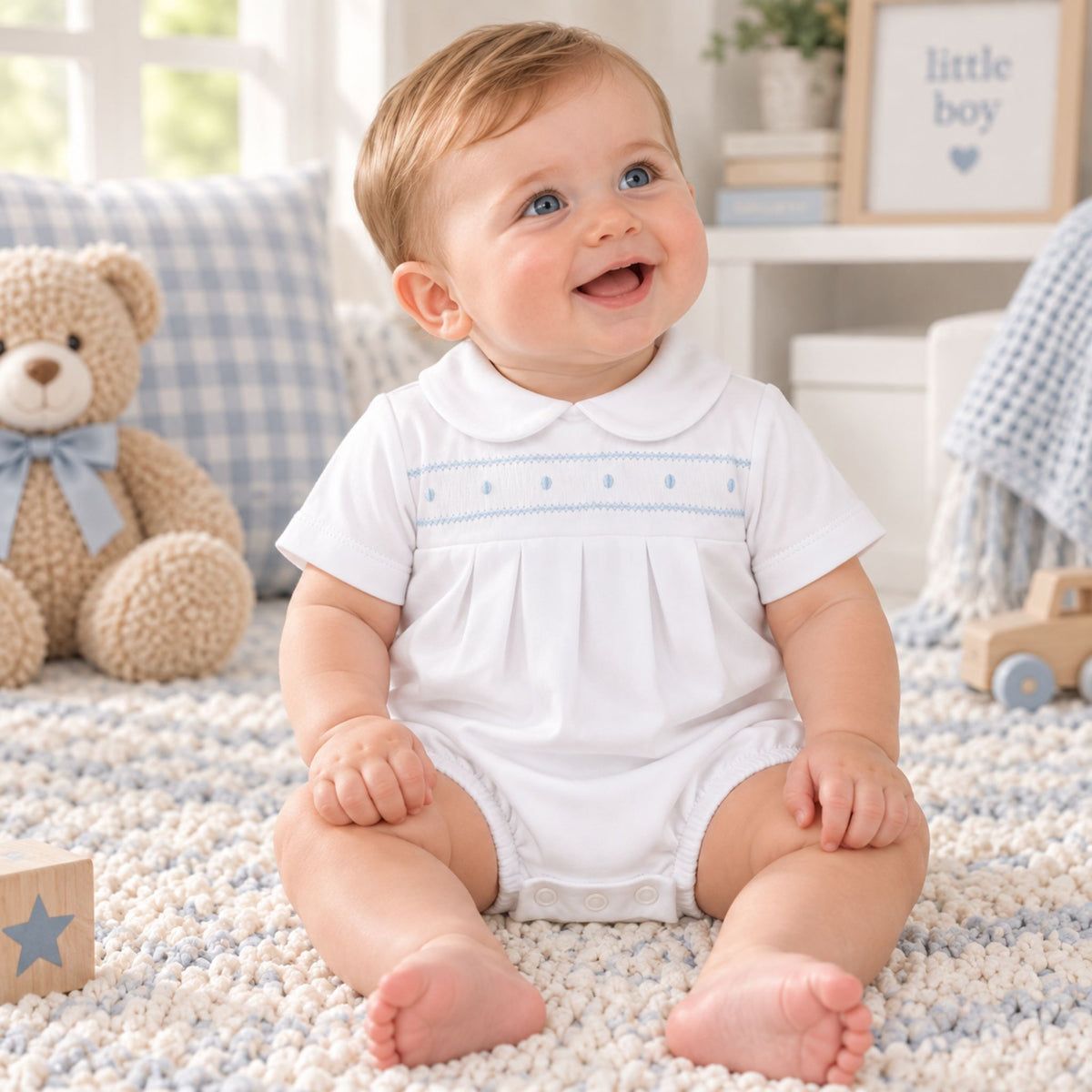 baby boy in white romper with blue embroidery