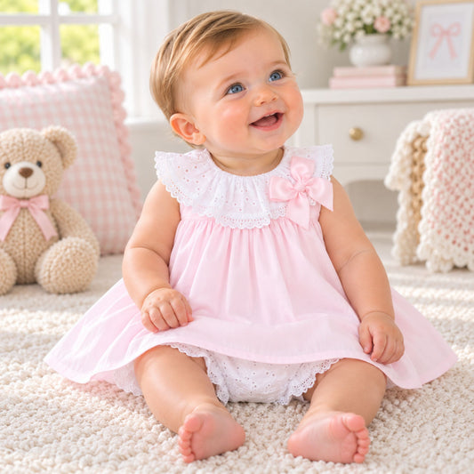 baby girl in pink dress with white bloomers.