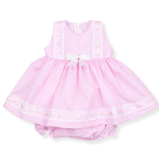 Pink baby dress with lace details on a white background