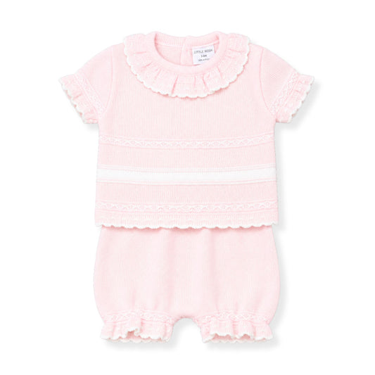 Pink baby outfit with ruffled details on a white background