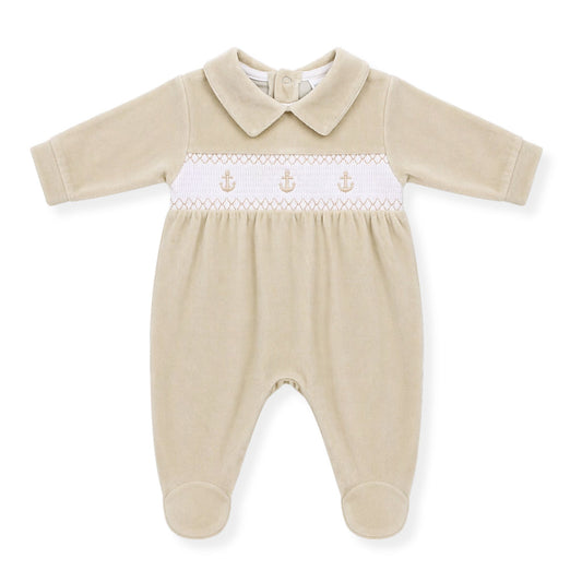 Beige baby boys babygrow with white smocked panel and anchor embroidery on a white background