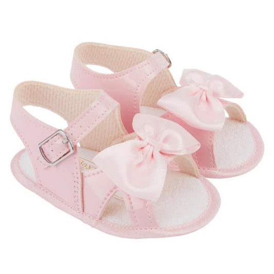 Pink baby sandals with bows on a white background