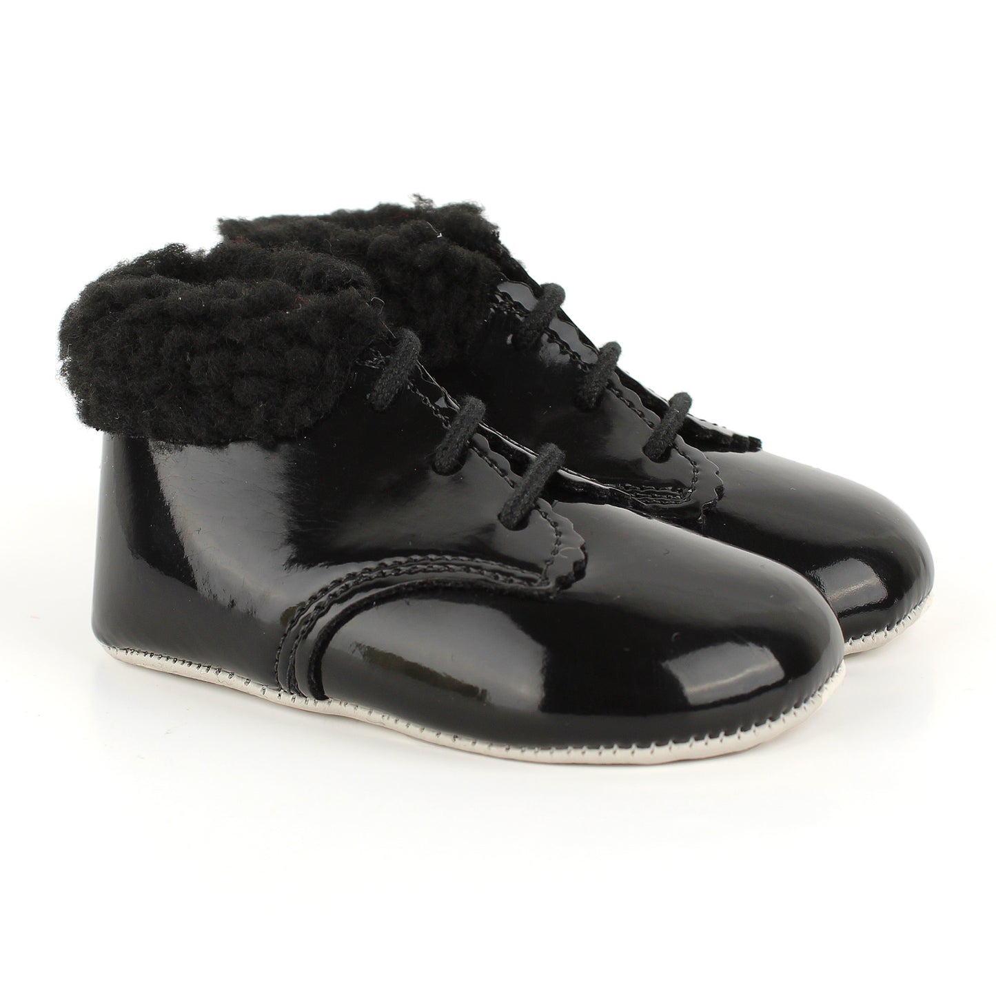 A pair of black patent leather baby booties with fluffy black faux-fur trim around the collar and black laces, shown on a white background.