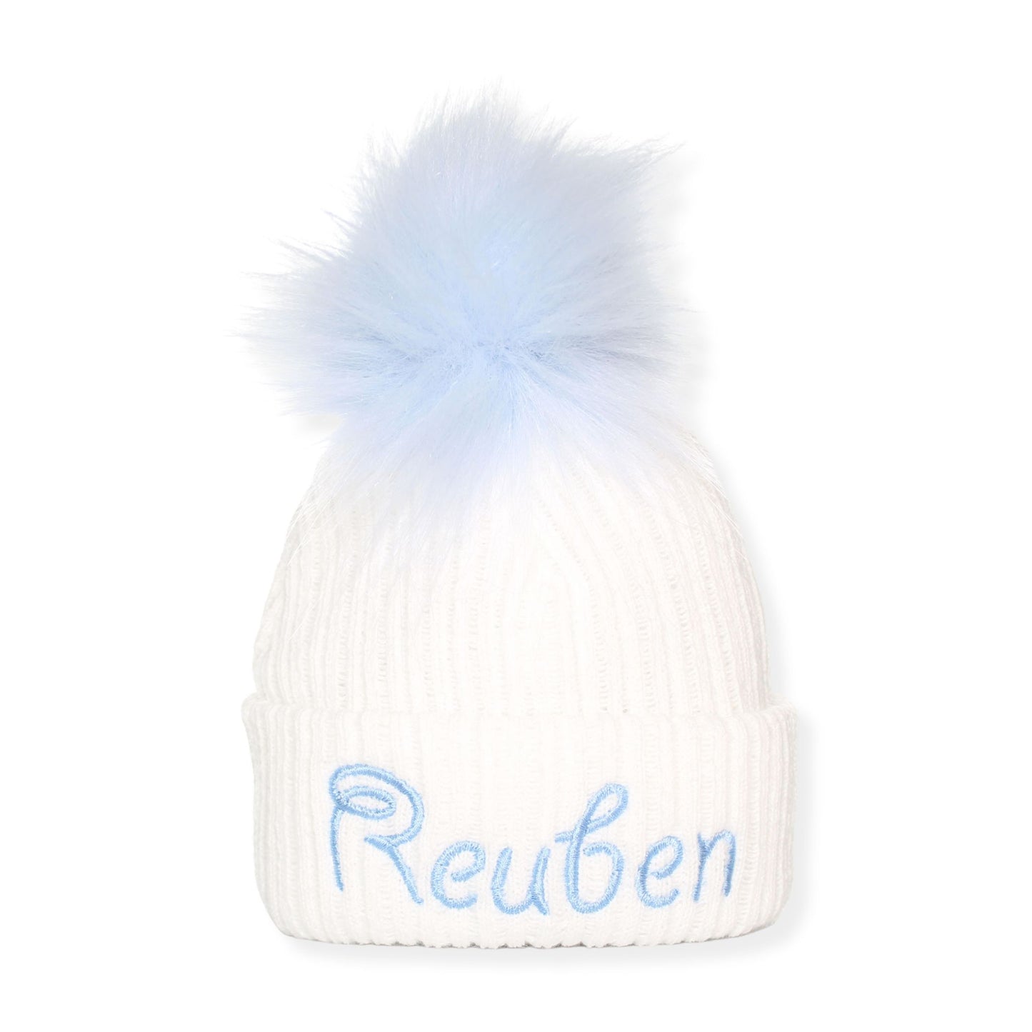 White beanie with blue fur pom-pom and embroidered name 'Reuben' on a white background