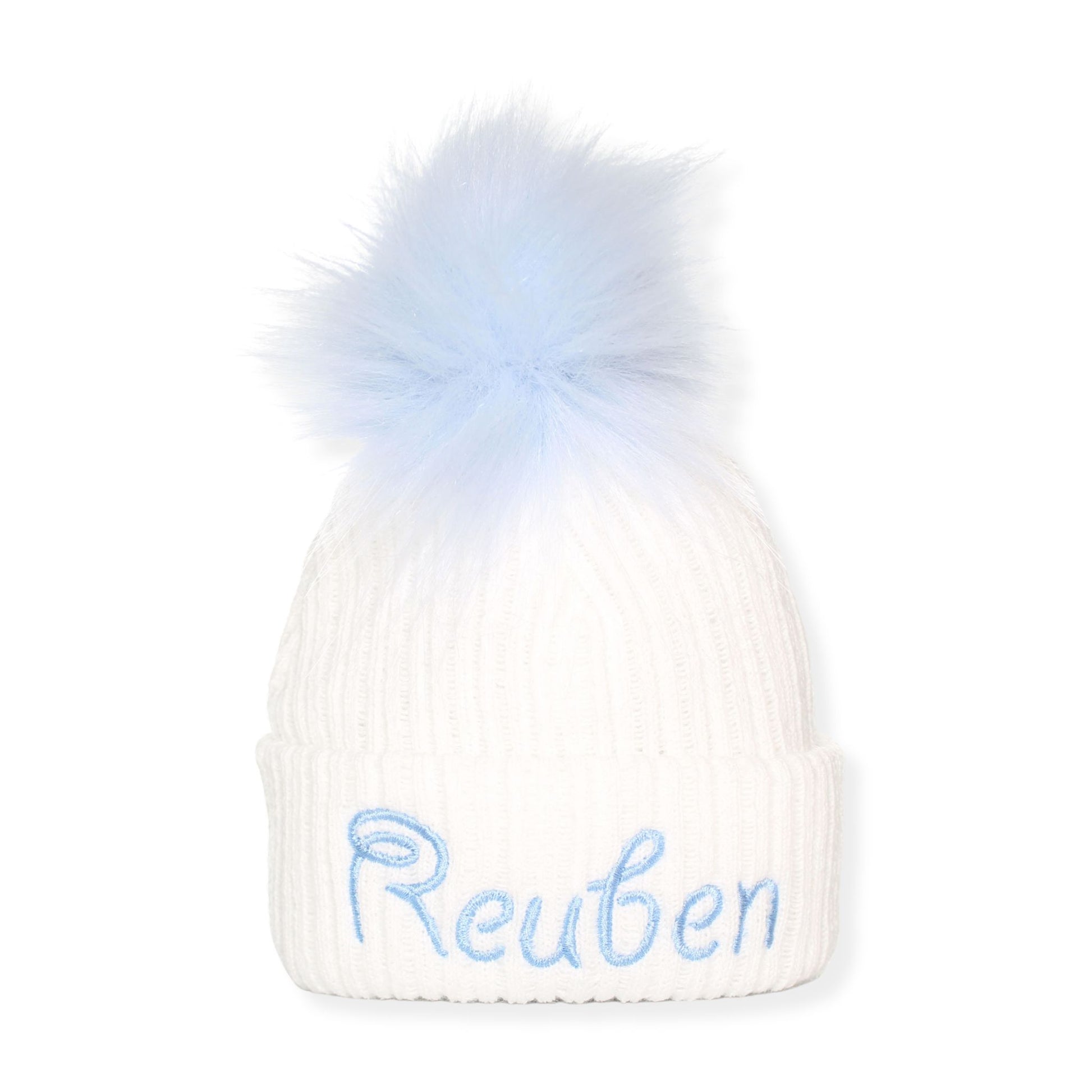 White beanie with blue fur pom-pom and embroidered name 'Reuben' on a white background