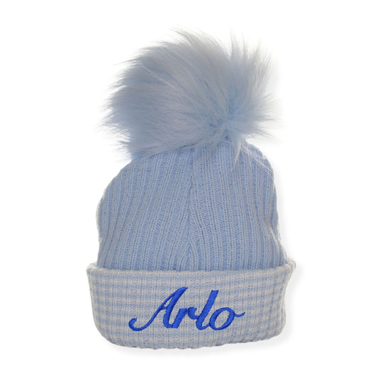 Blue beanie with a fluffy pom-pom and 'Arlo' embroidered on a white background