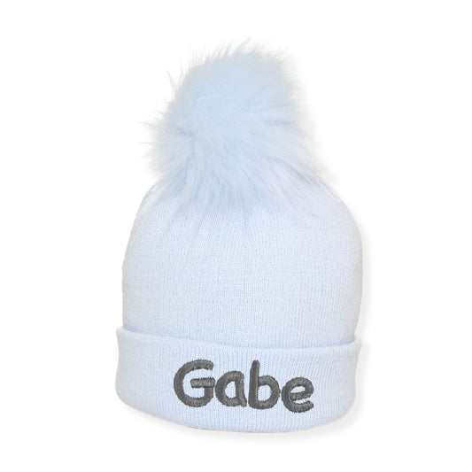Light blue beanie with a pom-pom and 'Gabe' embroidered on a white background